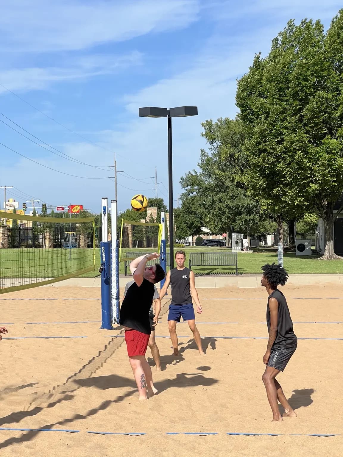 A Sandline player in red shorts reaches overhead while teammates read the play