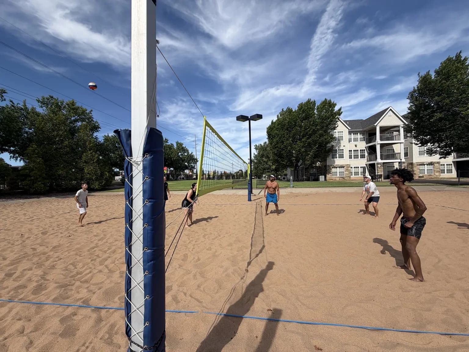 A ball crosses the court beside the net post as both teams stay ready for the next contact