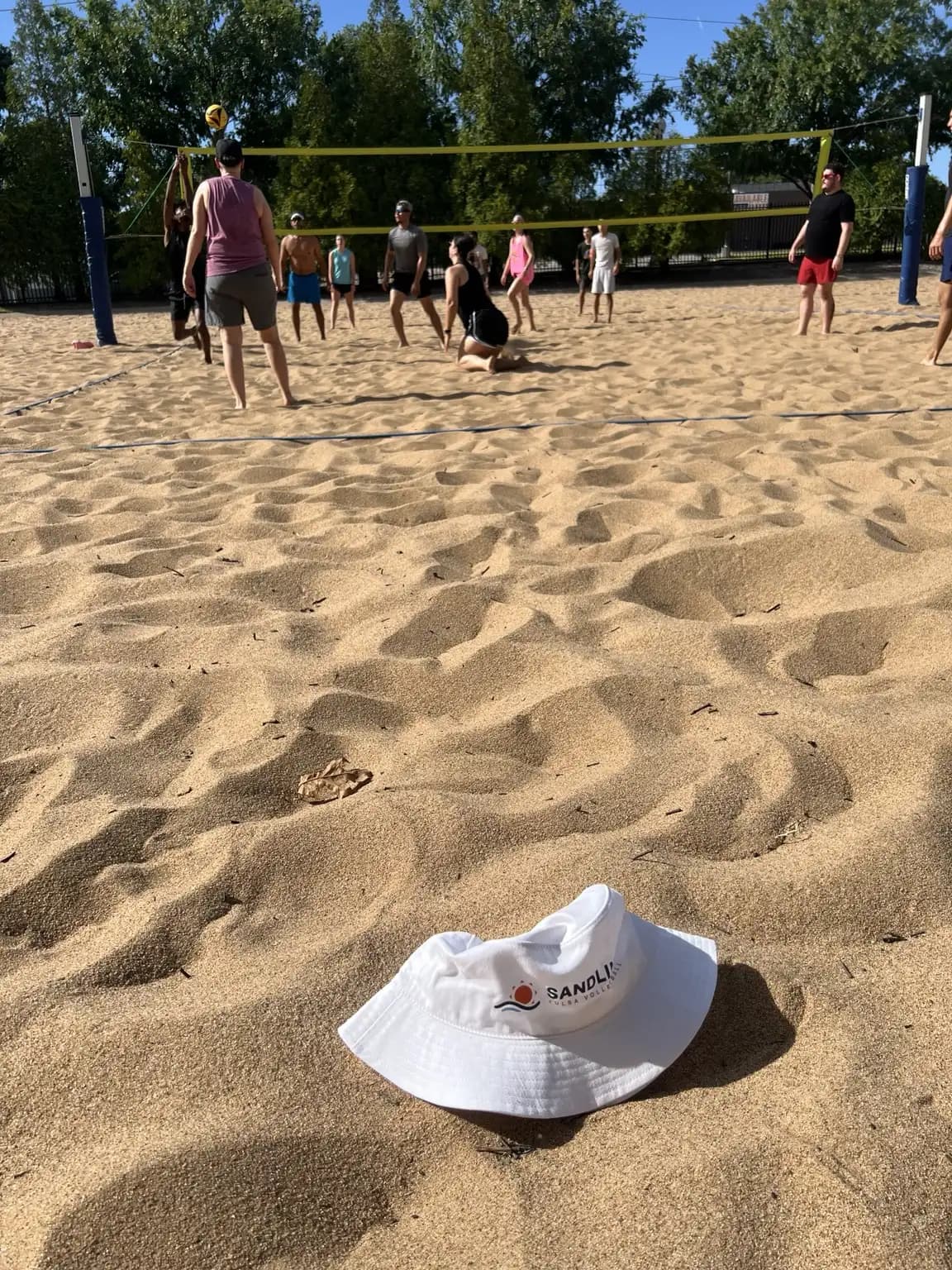 The Sandline bucket hat anchors the foreground while a player drops into defense