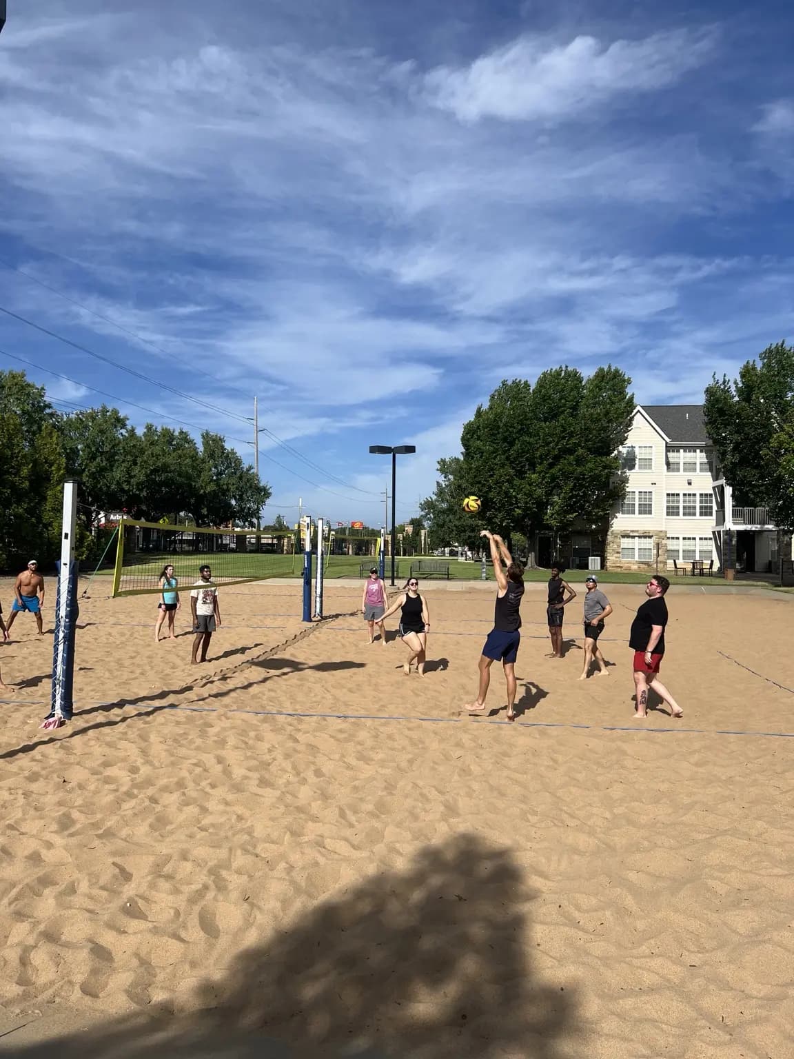 A Sandline player sets the ball overhead as teammates spread across the court