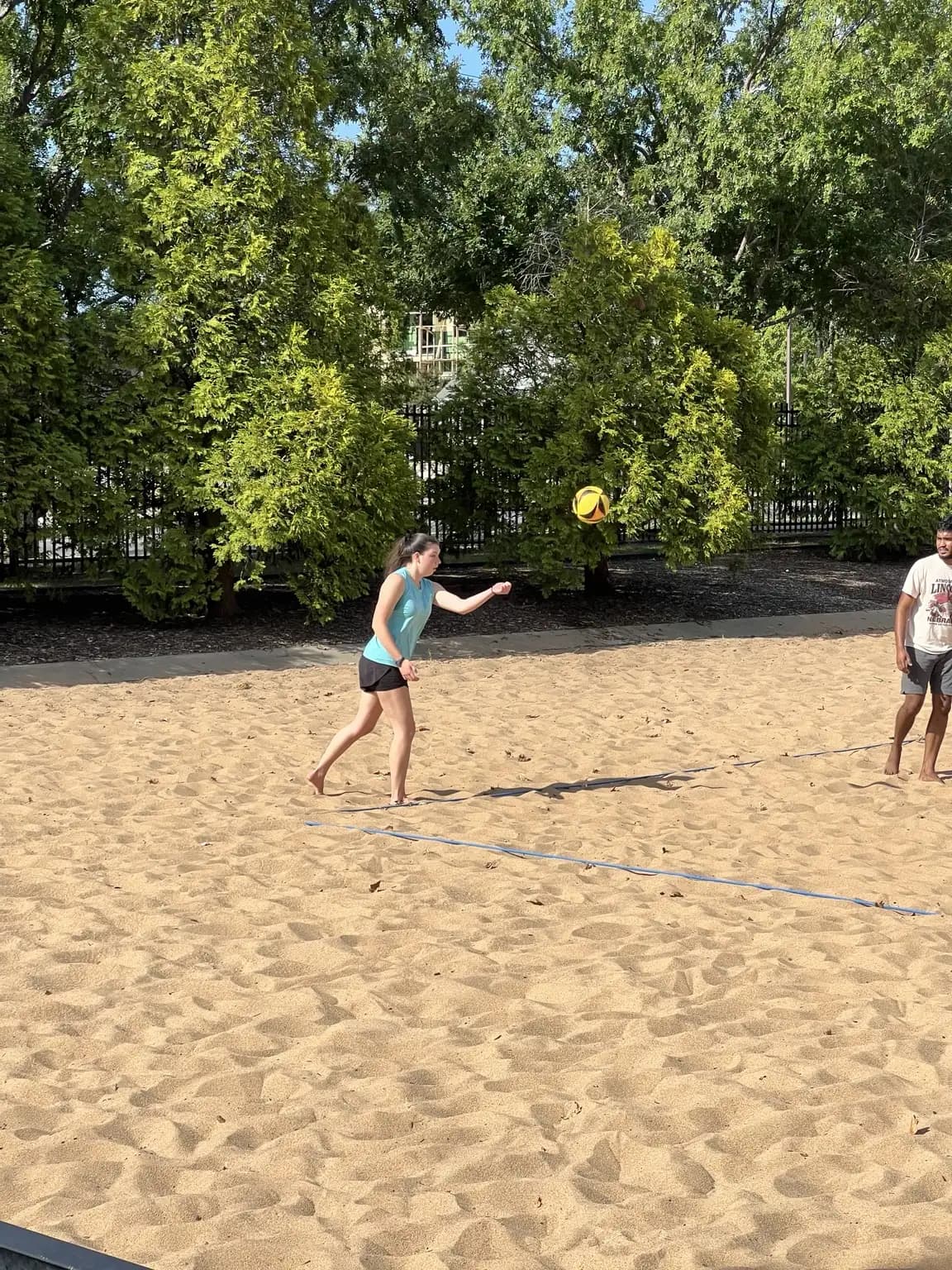 A Sandline player in teal makes contact with the ball from the back court