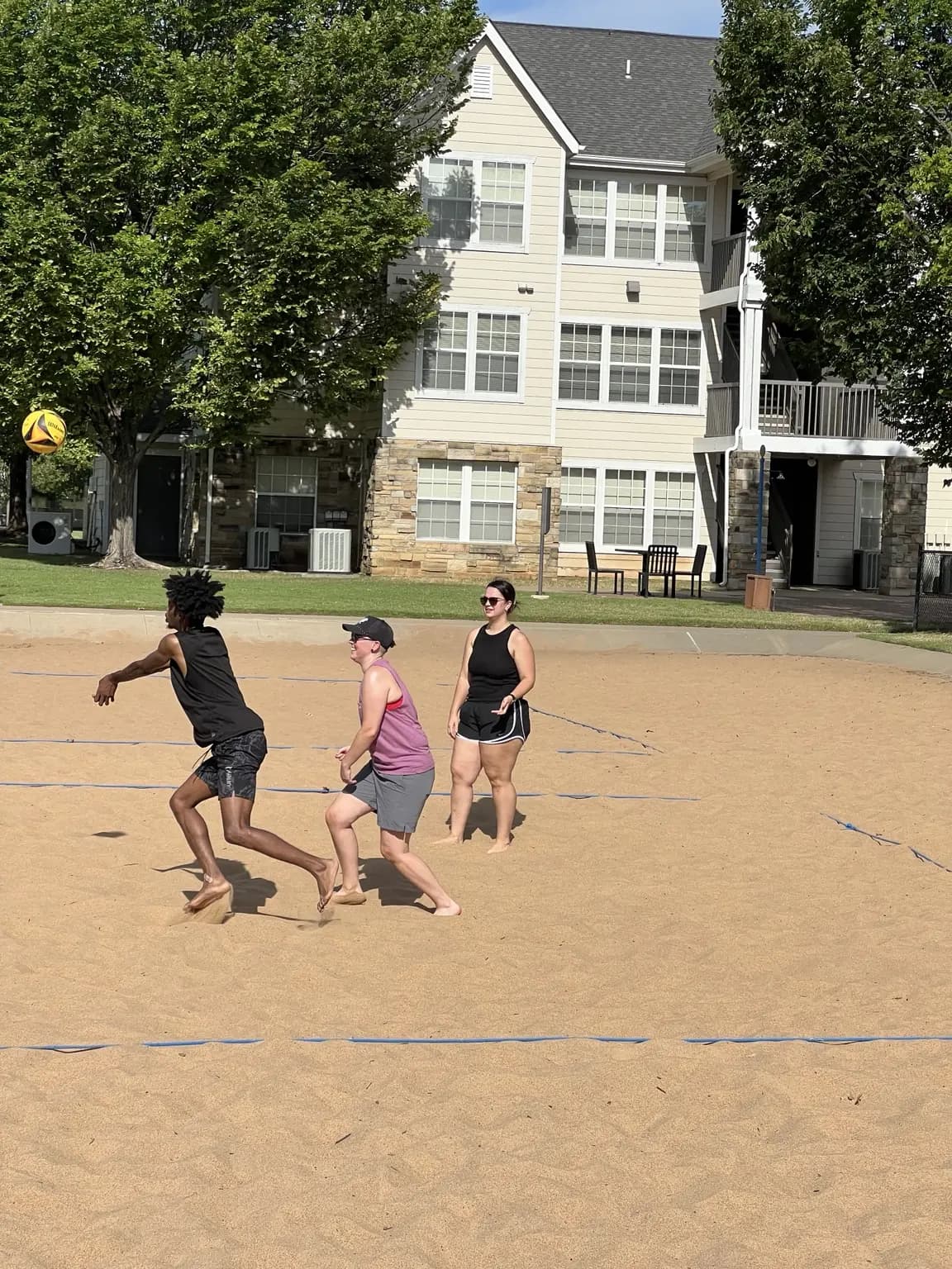 Three Sandline players chase a ball toward the left side of the court