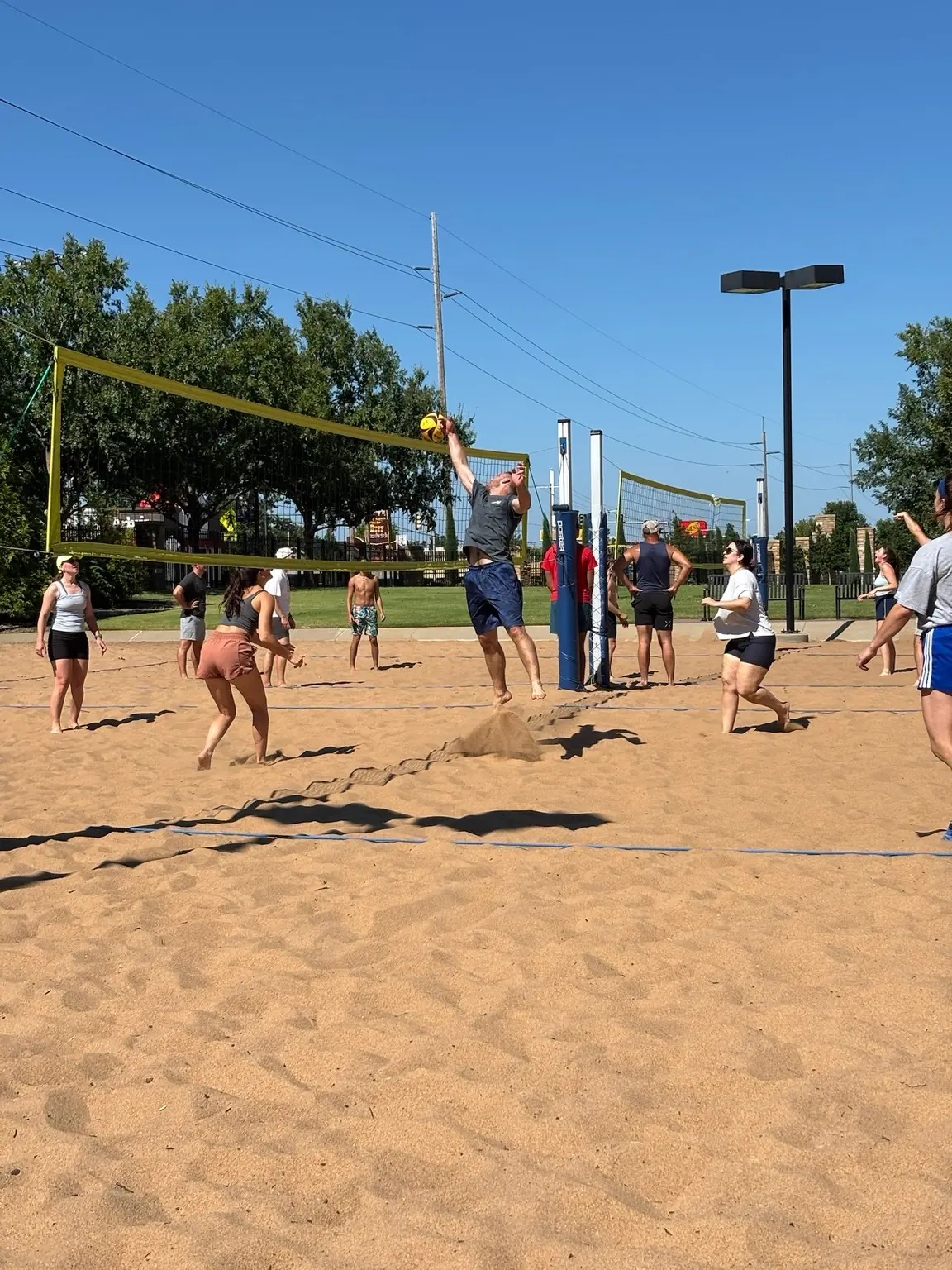 A Sandline player jumping at the net while both teams prepare for the next touch