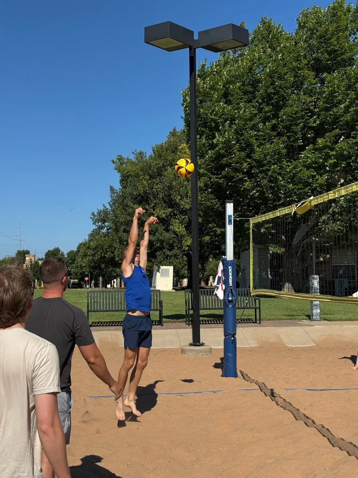 A Sandline player in blue reaching high to play the ball at the net