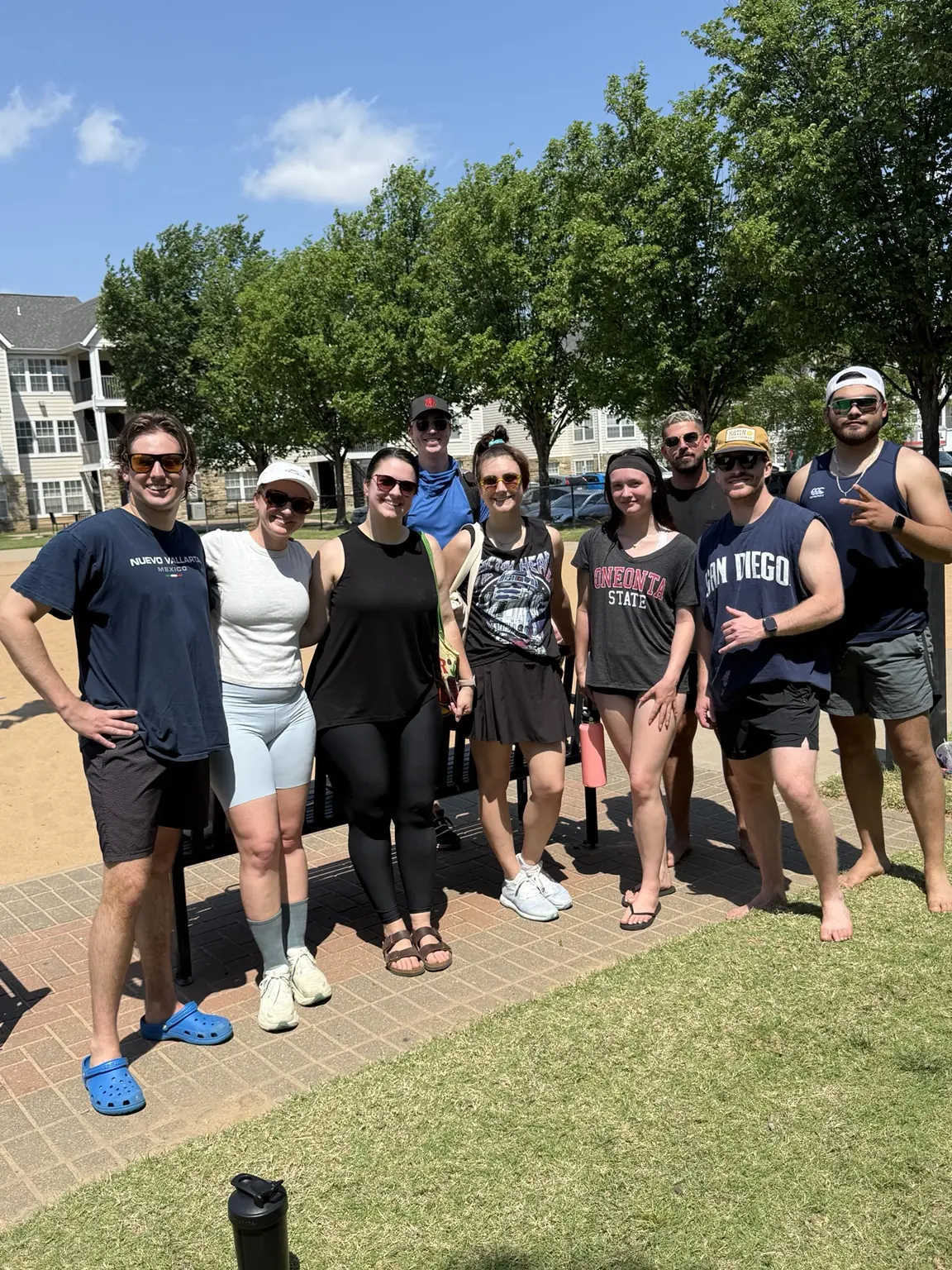 A group of Sandline players smiling together beside the courts